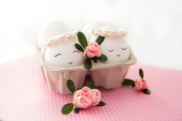 Easter background with cute smiling eggs and pink flowers. Selective focus.