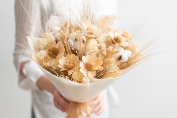 beautiful bouquet of mixed dried flowers in woman hand. the work of the florist at a flower shop....