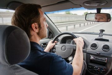  a man drives a car and looks in the rearview mirror