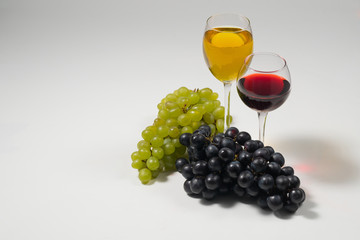 Bunches of grapes and glasses of wine on a white background