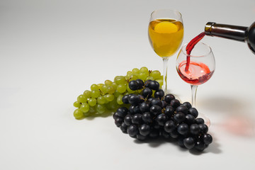 Bunches of grapes and glasses of wine on a white background