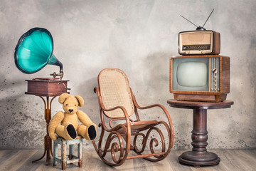 Retro TV receiver and old broadcast radio from circa 50s on wooden table, outdated gramophone,...