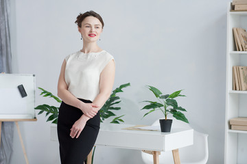 lovely girl in a white office stands near a white table