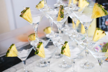 Champagne glasses, decorated with pineapple slices, stand a pyramid on the table.