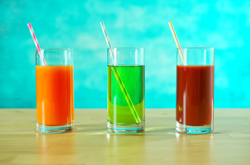 Fresh orange, apple and tomato juices in glasses with paper straws in bright table setting.