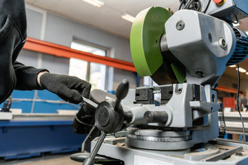 worker cuts a piece of material with a circular saw machine. Industrial engineer working on cutting a metal and steel with compound mitre saw with sharp, circular blade