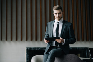 Fototapeta premium Young man drawing template for the web site associated with digital marketing, current trends and tendencies of UX / UI design. Businessman who rules his company remotely, like a freelancer