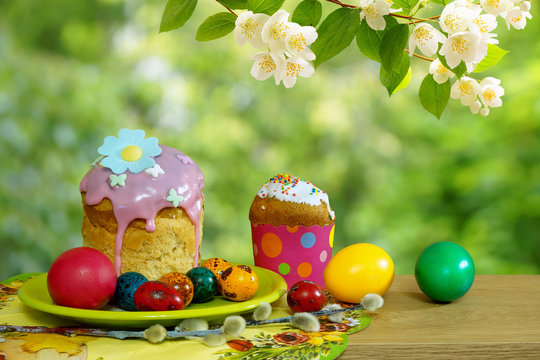 Easter still life. Easter cakes and colored eggs on the background of a blossoming garden.