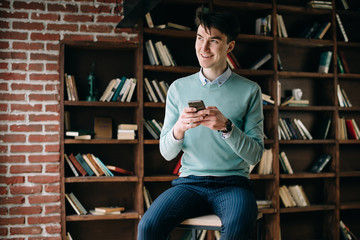 Young handsome student typing on his notebook his diploma. Student discussing on the phone universities's timetable. Education online. Work on freelance. Software development.