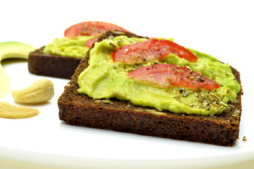 sandwich with avocado on a white plate nuts