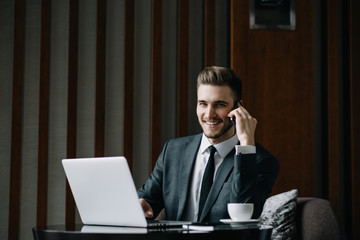 Stylish young man calling by the phone to solve business problems. Online consultation by phone. Freelancer discussing the development and planning of his online project. Outsourcing. Mobile services.