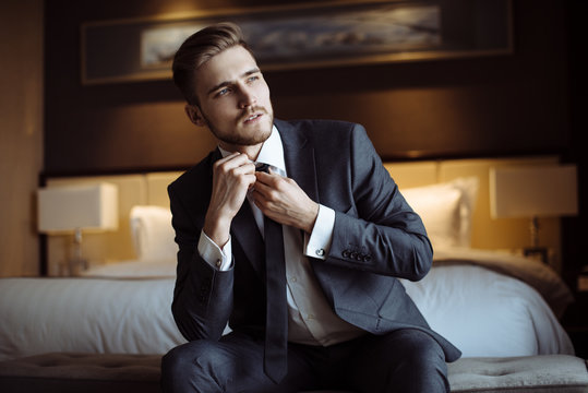 Young handsome man relaxing at his apartment in a hotel after business meeting. Business trip. Booking hotel during your vacation. Businessman in luxury room  of the expensive beautiful hotel. 