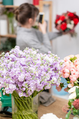 Work in Flower shop Beautiful fresh blossoming flowers lilac gillyflower and carnation. Blossom of pastel color in vases and pails.