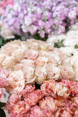 Floral carpet, flower texture, shop concept. Beautiful fresh blossoming flowers roses, spray roses, lilac gillyflower and carnation. Blossom of pastel color in vases and pails. Top view.