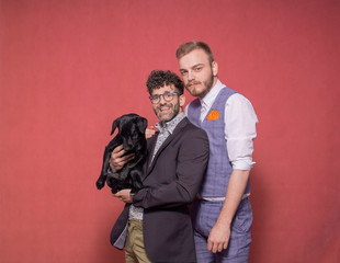 gay couple photo-shoot in studio, holding a puppy in arms.