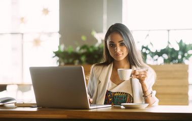 Beautiful girl working out a plan of the project and concept. Girl paints a website design on a laptop. student prints a message on the phone in the messenger. Development. Digital marketing