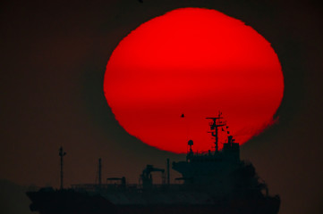 昇る太陽を横切る船の影