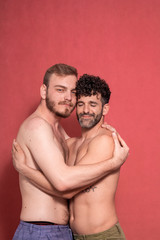 sexy gay couple, hugging each other. eyes closed, and looking to camera, calm.