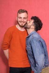 young gay couple, one kissing other one in cheek.