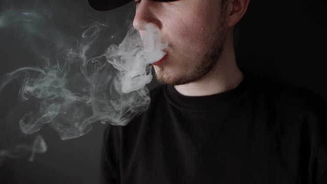 man in Black Suit vaping electronic cigarette makes smoke clouds