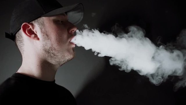 man in Black Suit vaping electronic cigarette makes smoke clouds