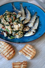 Grilled sardines and salad made with chicory, white beans and dried tomatoes. Selective focus.