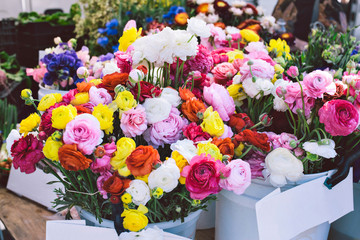 Buckets of beautiful and colorful flower bouquets are for sale at a farmers market stall