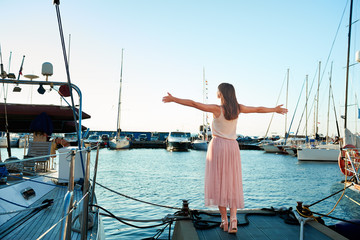 young woman is standing back against the background of beautiful yachts