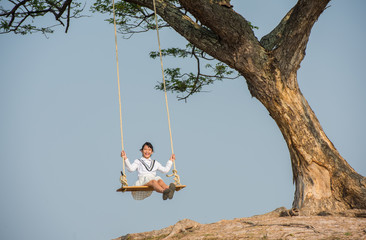 Girl on swings under the trees happily