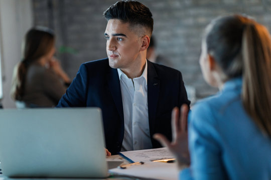 Young businessman ignoring his female colleague while she talking to him in the office.