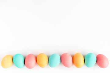 Fototapeta na wymiar Colorful handmade Easter eggs lined on white background. Flat lay.