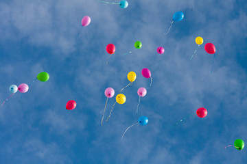 Colorful toy balloons floating in the blue sky.
