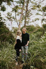 Cute Young Attractive Dating Couple Looking, Smiling, and Laughing in the Dense Isolated Green Tropical Forest Jungle