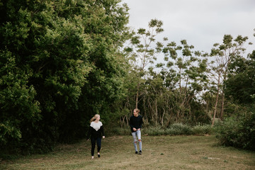 Fototapeta premium Cute Young Attractive Dating Couple Looking, Smiling, and Laughing in the Dense Isolated Green Tropical Forest Jungle