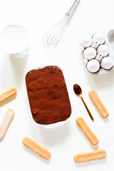 Preparing a tasty tiramisu , step by step visual guide, second lay of cream is pored followed by a sprinkle of chocolate powder as the final retouch for the perfect tiramisu cake,on a white board, top