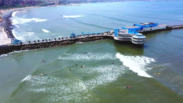 Drone aerial view of La Rosa Nautica by the sea in Makaha Beach. Group of surfers learning to surf in a bright summer day at Miraflores district, Lima, Peru.
