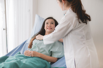 Fototapeta premium Doctor using stethoscope checking to asian women patient for listening heart rate on sickbed in hospital room