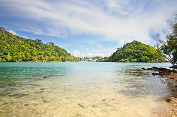 Obraz premium Crystal clear tropical sea with island covered with rainforest on horizon at the Koh Chang island, Thailand.