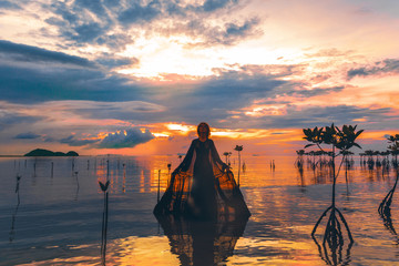 young woman standing in water at sunset silhouette