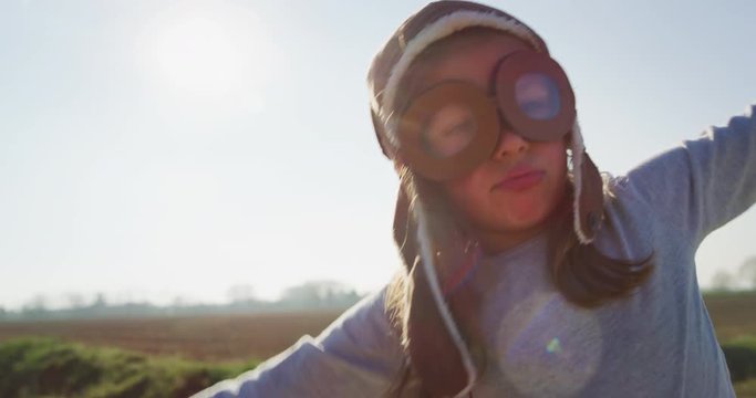 Authentic shot of cute little girl with aviator hat having fun and smiling in camera on a spring nature background in a  sunny day.