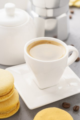 Yellow french macarons with fruit filling and a cup of espresso.