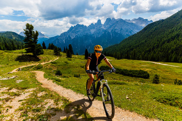 Woman cycling on electric bike on mountain trail. Woman riding on bike in Dolomites mountains...