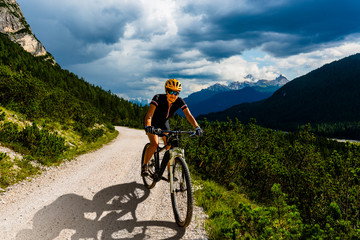 Obraz premium Woman cycling on electric bike on mountain trail. Woman riding on bike in Dolomites mountains landscape. Cycling e-mtb enduro trail track. Outdoor sport activity.