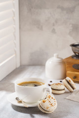 Cup of black coffee and chocolate macarons for dessert.