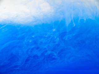 Blue acrylic ink dissolving into water, close up. Abstract background. Blue paint in liquid. Abstract acrylic clouds in liquid. Ink waves in water, abstract pattern. Blurred background