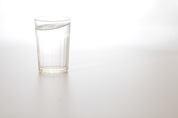 Water wave in transparent glass and puddle on gray background. purified fresh drink water on table