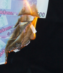 five hundred euro fakes are burning on a black background