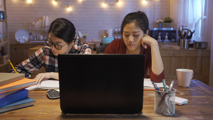 two skilled young asian women watching online lesson on modern laptop computer for distance...