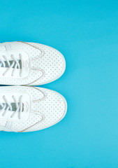 Women's sneakers on a blue background top view. Women's shoes. Fashion blog or magazine concept. Flat lay, top view minimal background. Place for your design, text.