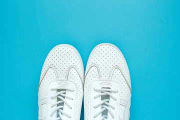 Women's sneakers on a blue background top view. Women's shoes. Fashion blog or magazine concept. Flat lay, top view minimal background. Place for your design, text.